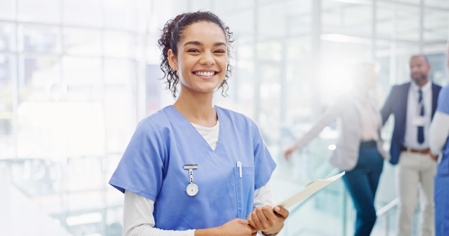 Smiling medical assistant holding a document in a clinic lobby