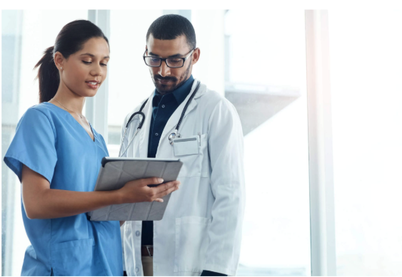 Medical assistant in blue scrubs reviewing patient records with a Physician